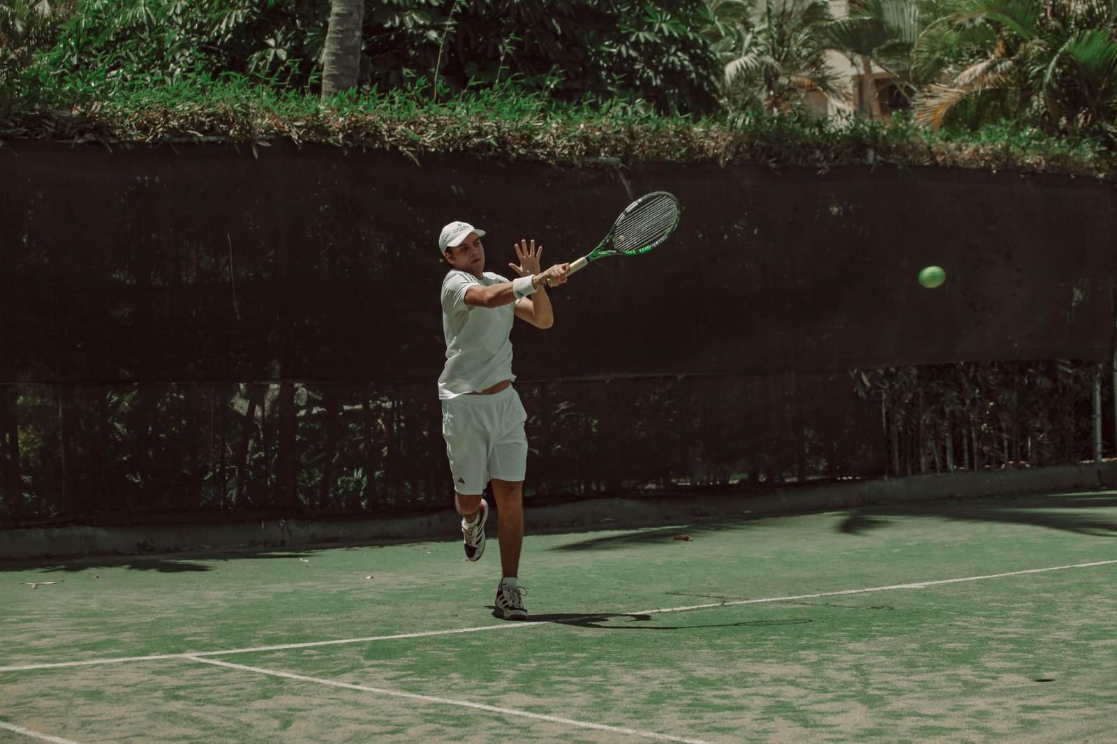 A tennis player hitting a forehand on an outdoor hard court