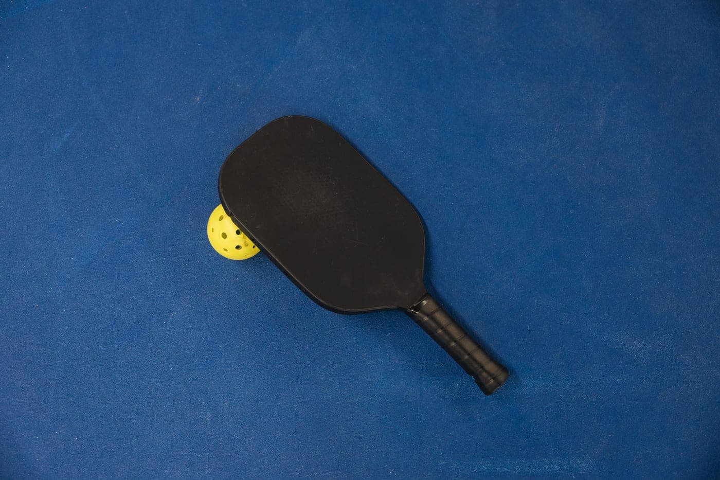 A pickleball paddle and ball on a court